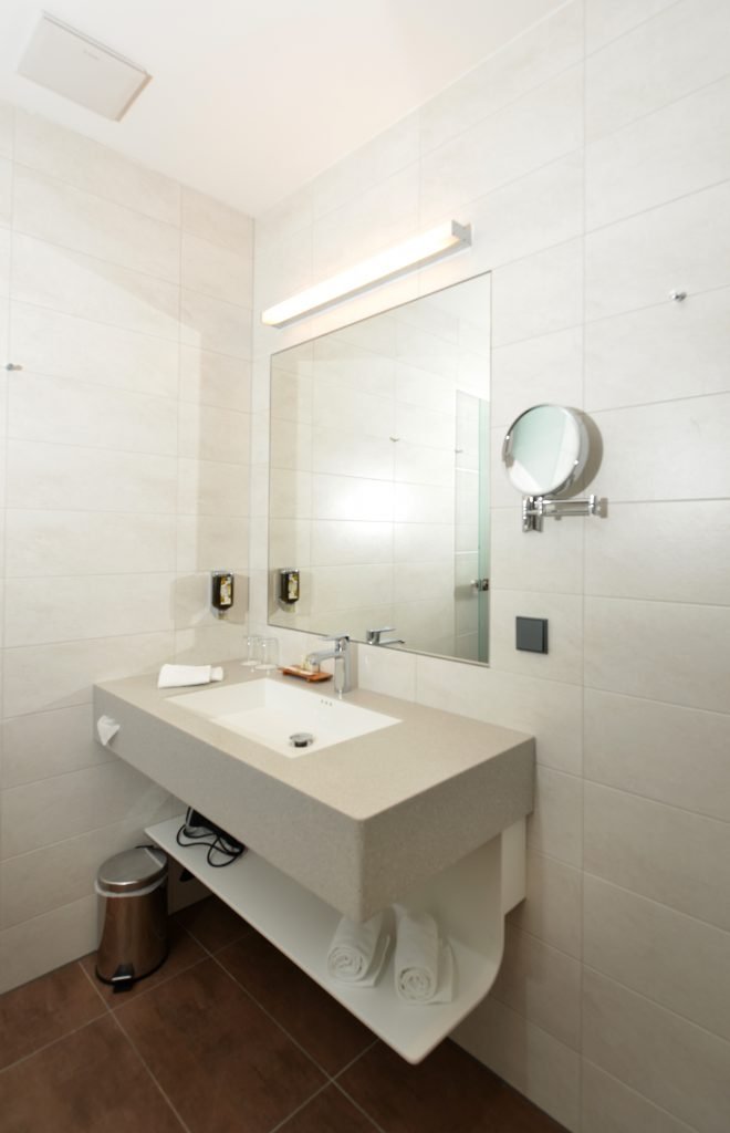 Helles Badezimmer einer Suite im ArtHotel Kiebitzberg mit großem Spiegel, Designwaschtisch und Kosmetikspiegel