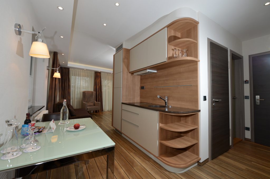Wohnbereich einer Suite im ArtHotel Kiebitzberg mit Küche, Glas-Esstisch, Sitzecke und Holzboden