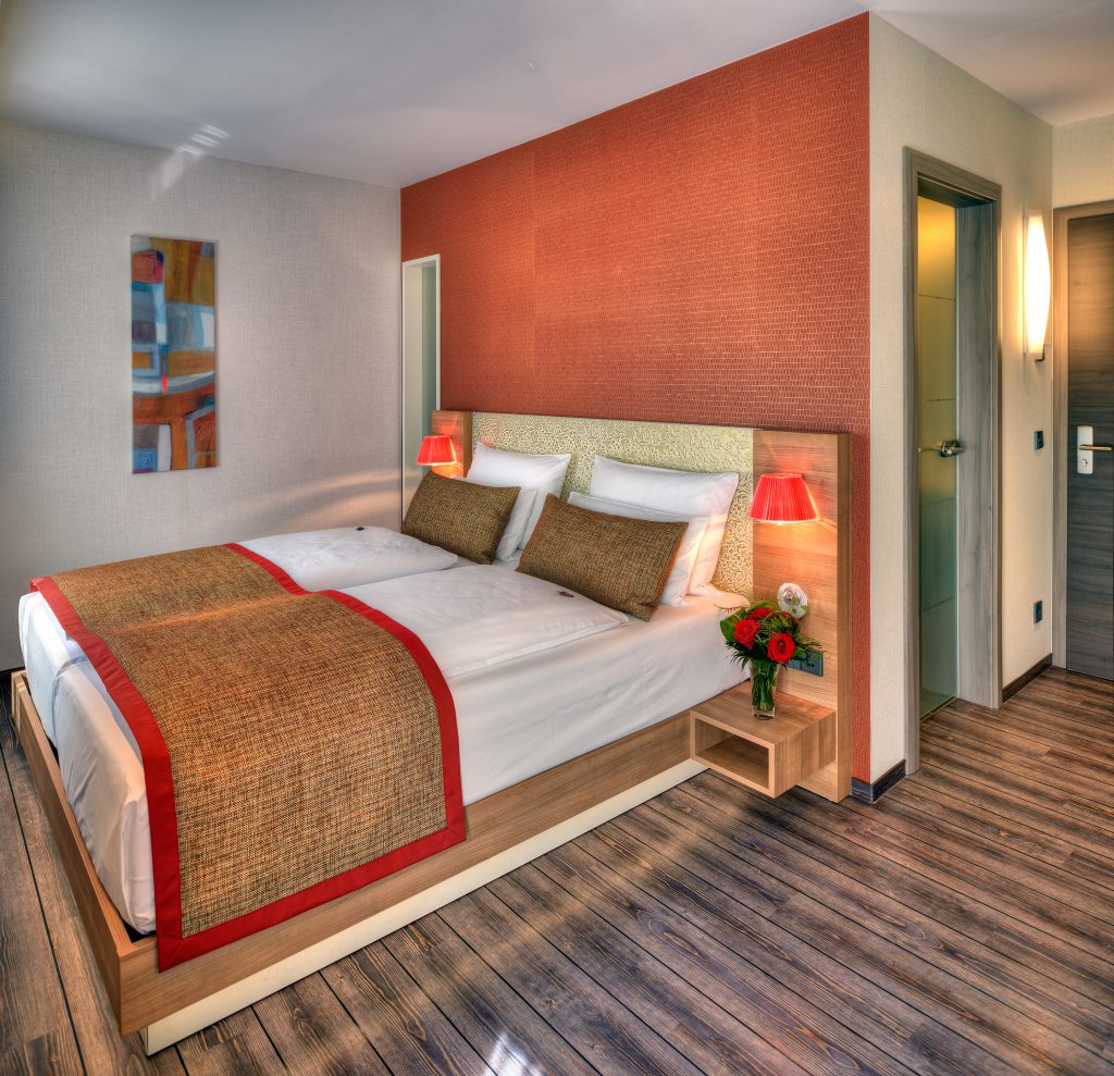 Comfort-Doppelzimmer im ArtHotel Kiebitzberg mit Doppelbett, terrakottafarbener Wand, Kunstbild und Holzdielenboden