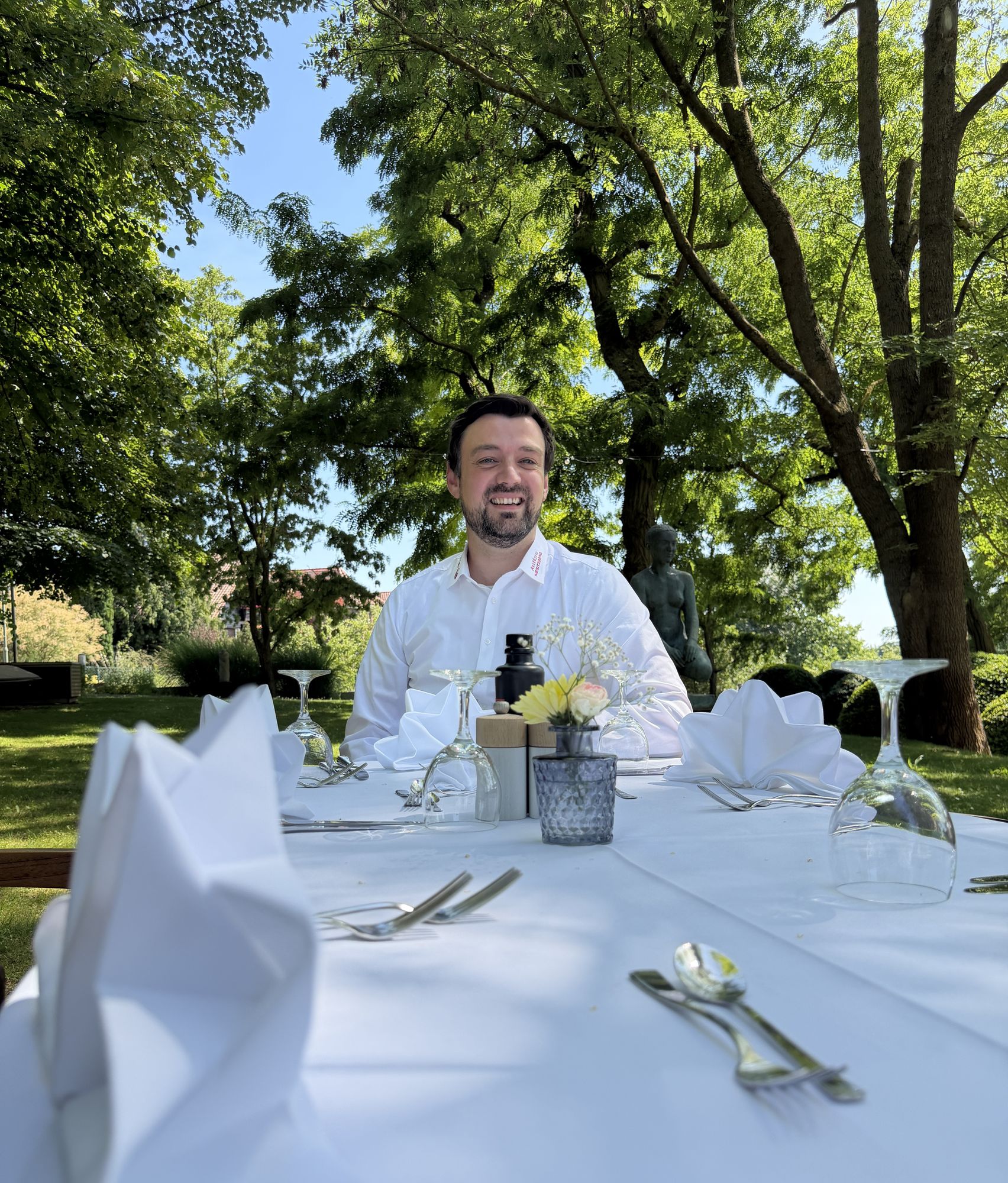 Smiling host Felix Goder at a festively laid table in the sunny hotel garden