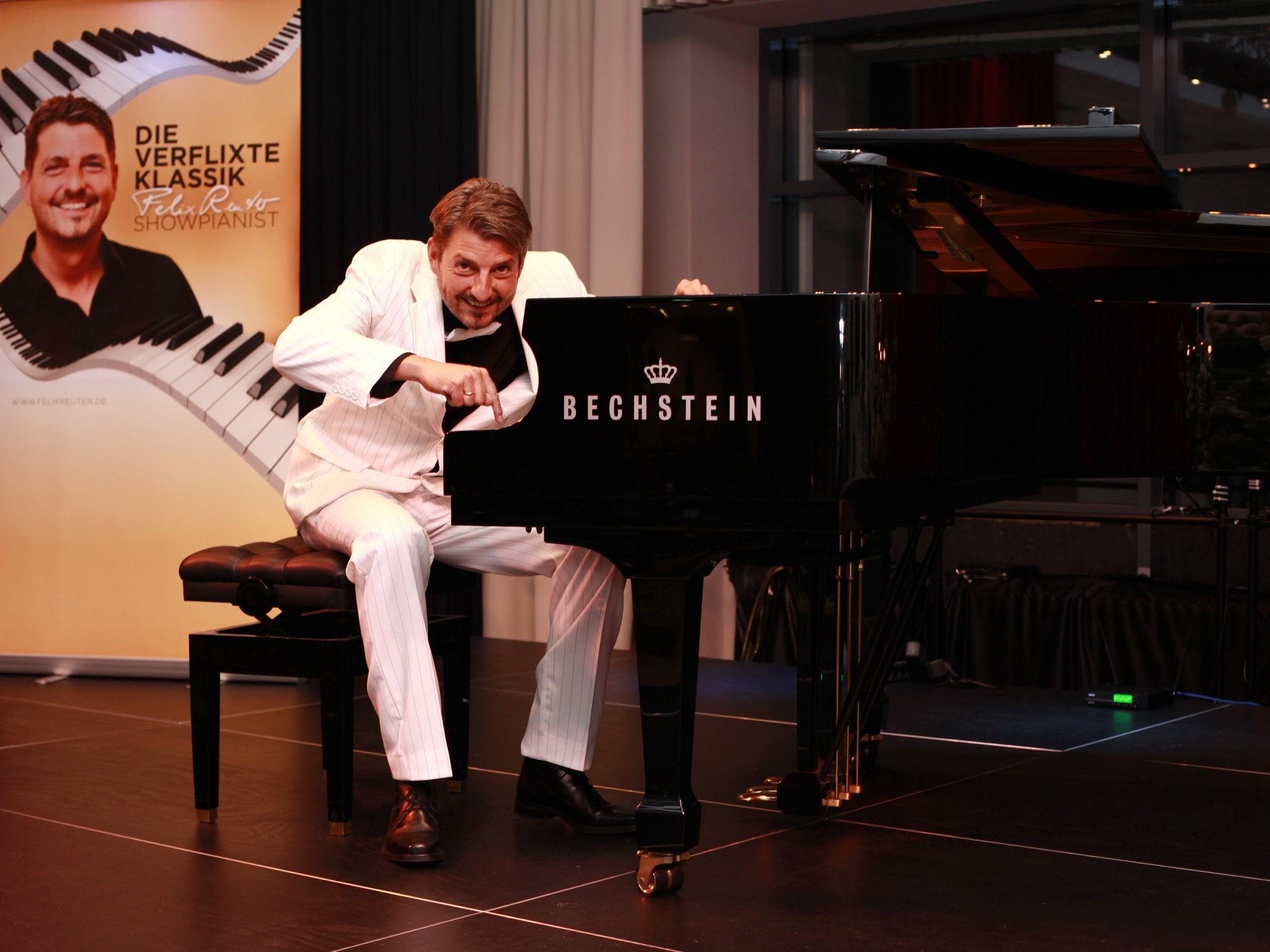 Showpianist Felix Reuter im weißen Anzug am schwarzen Bechstein-Flügel beim Konzert im ArtHotel Kiebitzberg