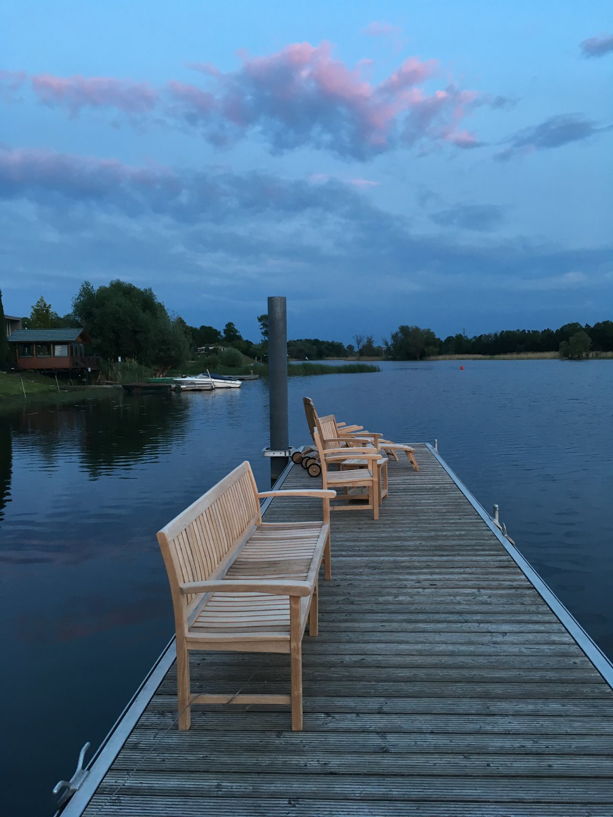 Holzbänke und Liegestühle auf einem Steg an der Havel in der Abenddämmerung nahe dem ArtHotel Kiebitzberg