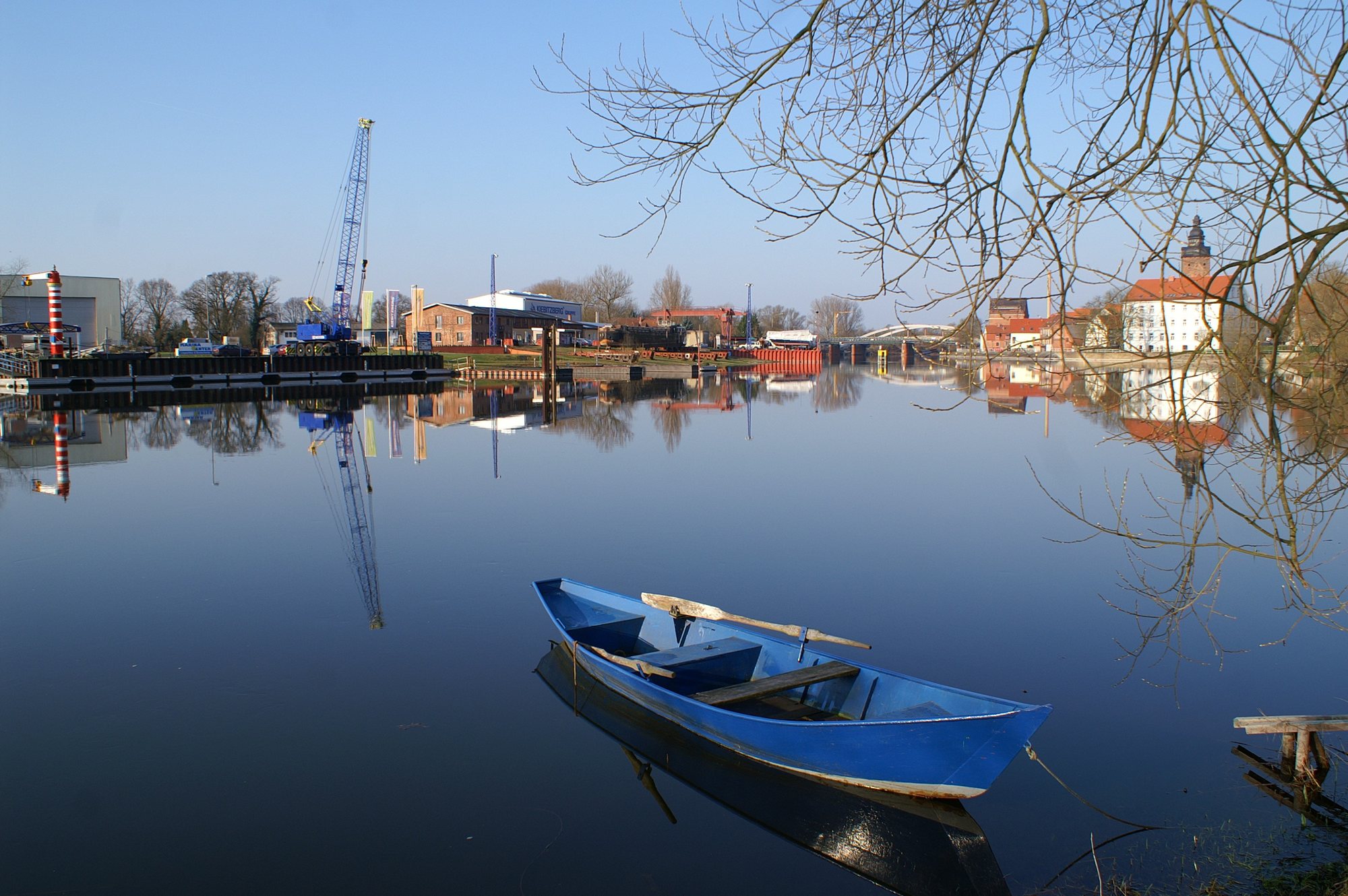 Blaues Ruderboot auf spiegelglatter Havel vor dem Werftgelände und Dom in Havelberg
