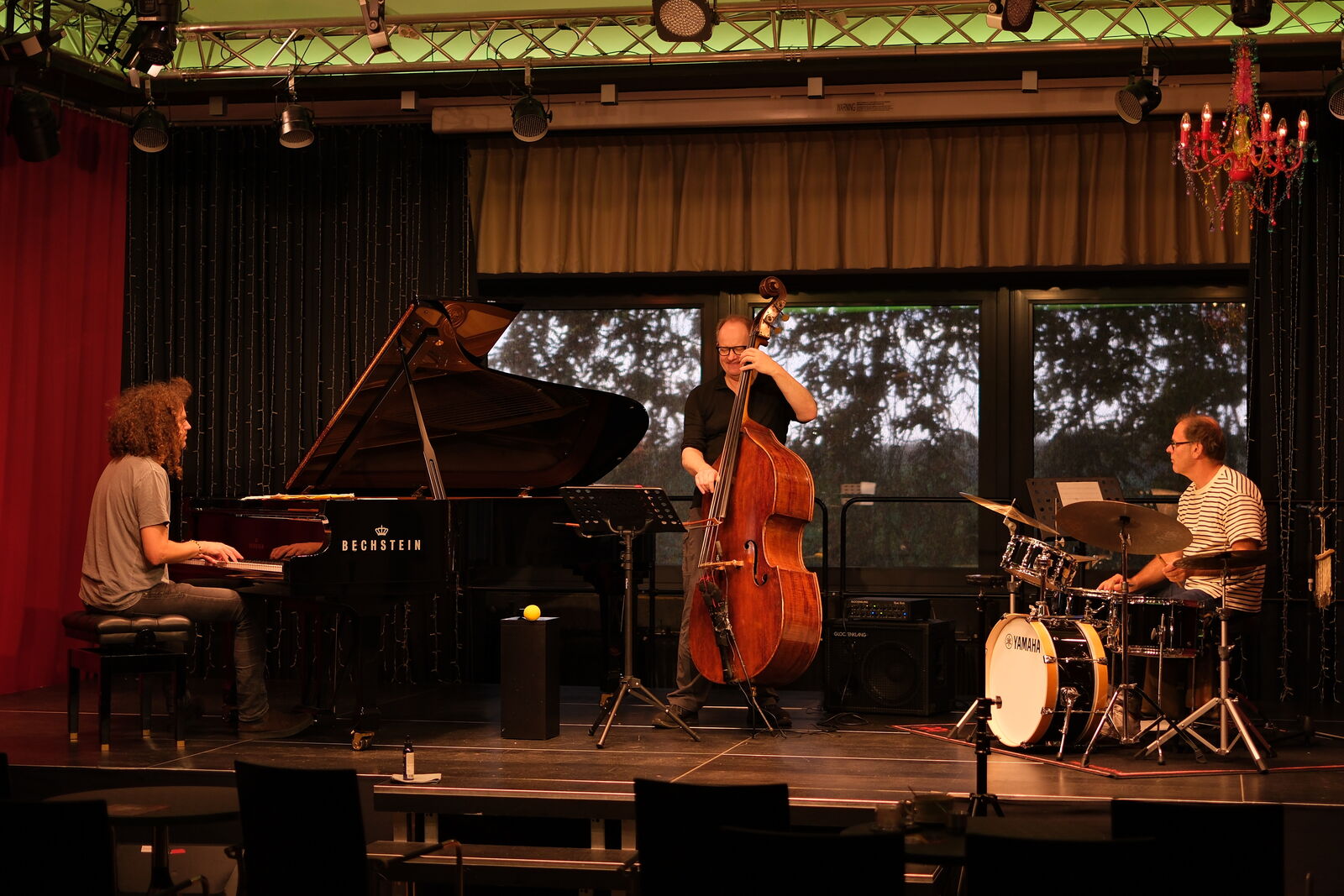 Das Dieter Ilg Trio auf der Bühne im KunstQuartier mit Flügel, Kontrabass und Schlagzeug