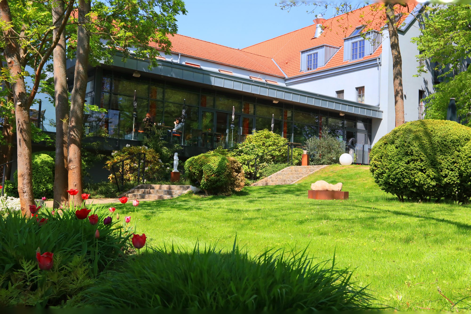 Akkurat geschnittene Buchskugeln und eine Skulptur im grünen Park des ArtHotel Kiebitzberg