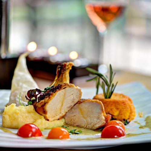 Signature-Gericht mit gebratenem Geflügel, Polenta und Kirschtomaten im Restaurant Schmokenberg