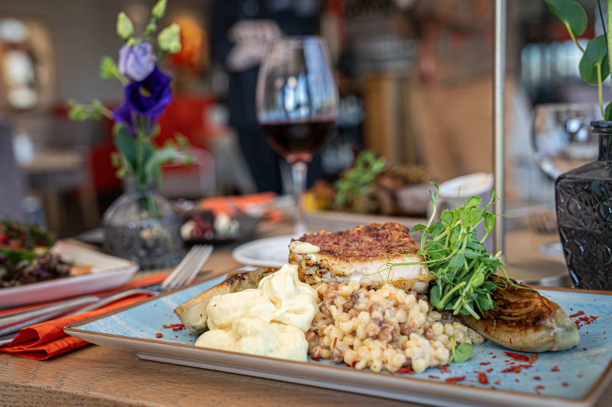 Angerichtetes Fischgericht mit Graupenrisotto, Sauce und Rotwein im Restaurant Schmokenberg