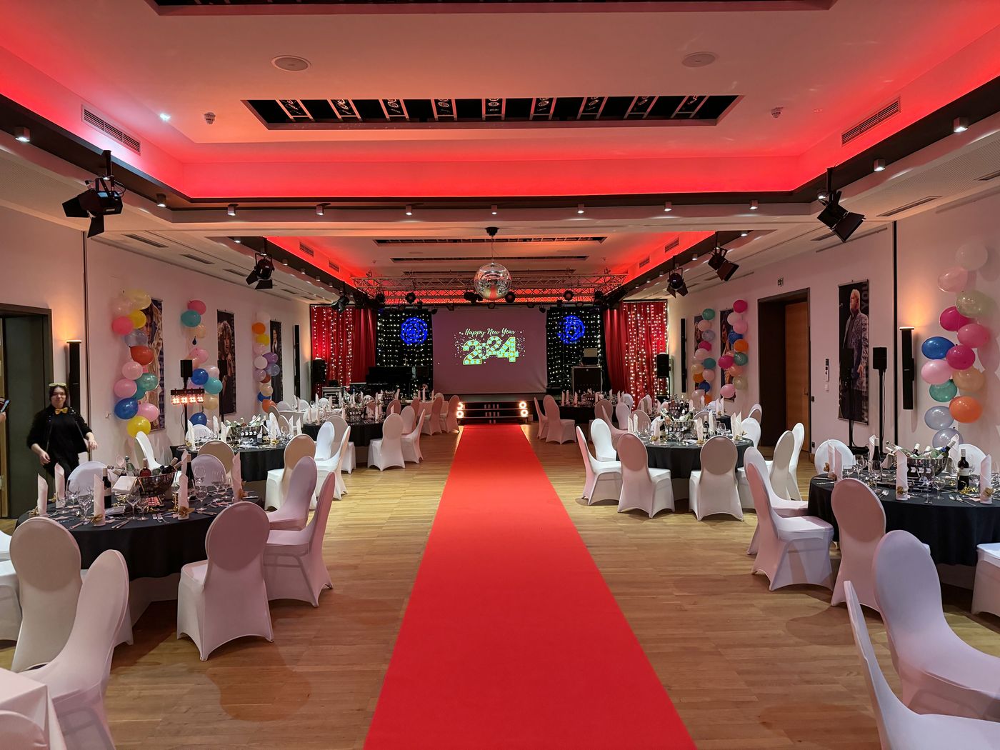 Ballroom of ArtHotel Kiebitzberg for the New Year’s Eve gala with a red carpet, stage, disco ball and a Happy New Year 2024 projection