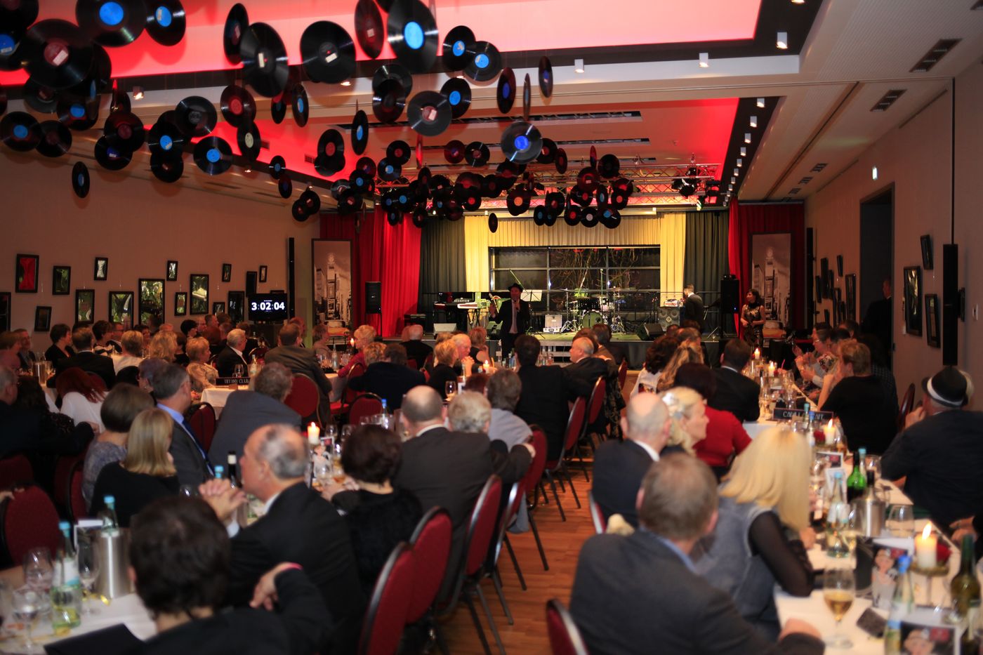 Packed ballroom with vinyl-record ceiling decoration and a stage at the New Year’s Eve party