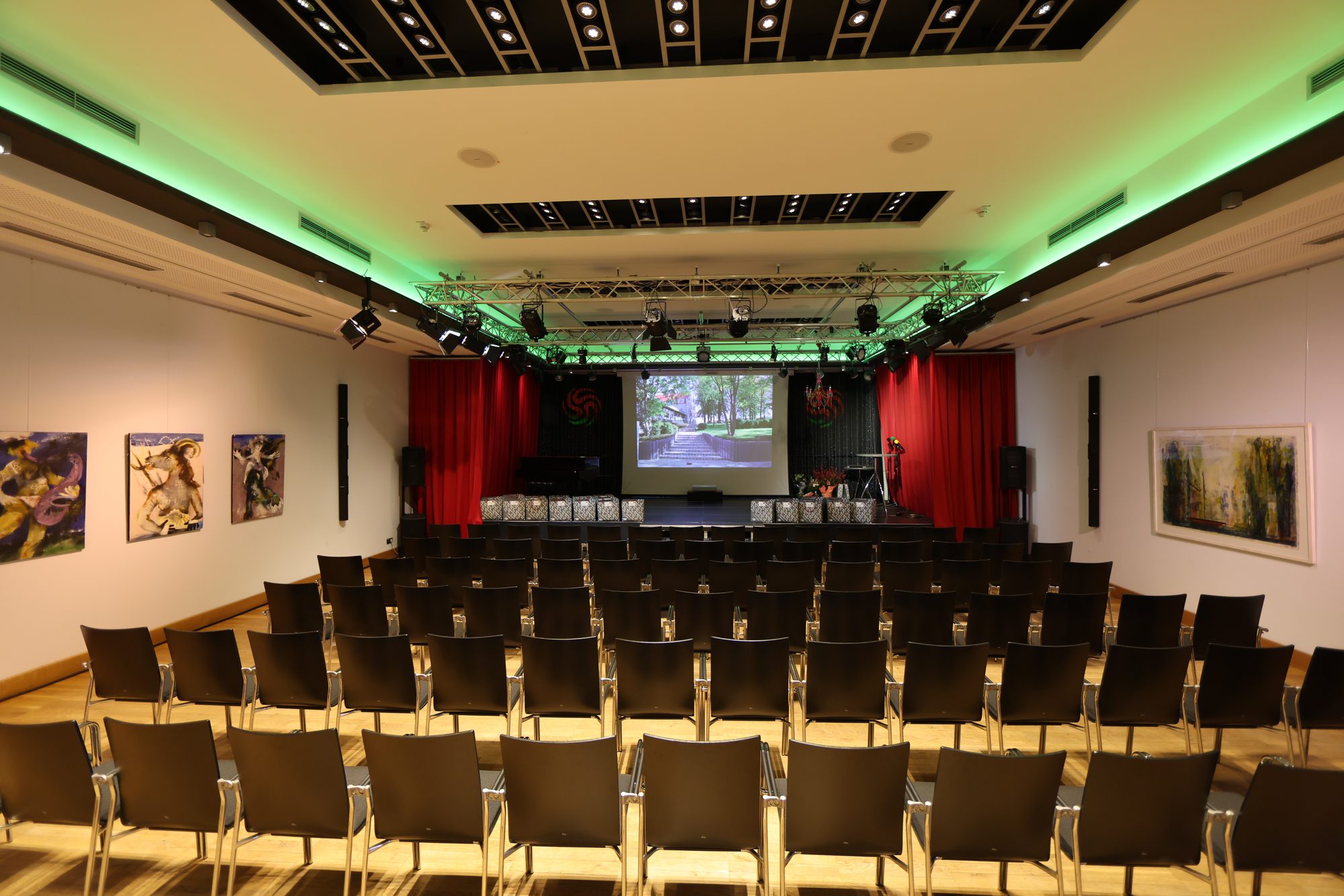 Großer Festsaal im ArtHotel Kiebitzberg mit Reihenbestuhlung, Bühne, Leinwand und grüner Deckenbeleuchtung
