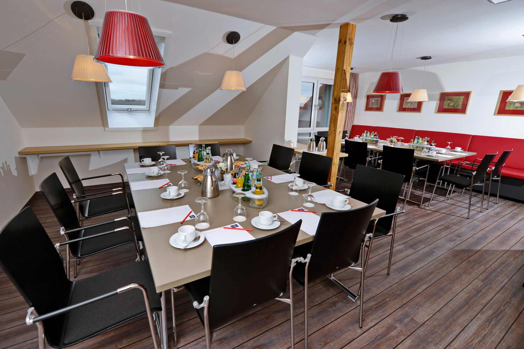 Tagungsraum mit Havelblick im ArtHotel Kiebitzberg mit langer Tischtafel, schwarzen Stühlen, roten Lampen und Dachfenstern
