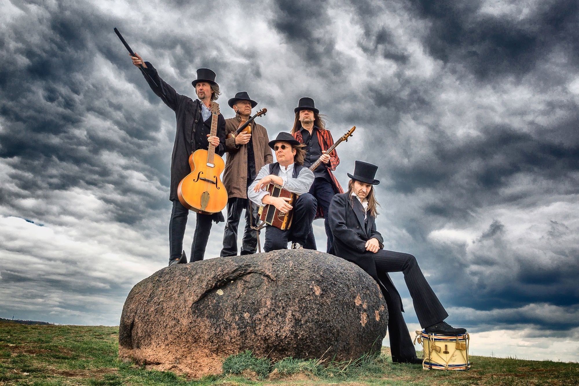 Fünfköpfige Band THE ABERLOURS mit Instrumenten auf einem Felsblock unter dramatischem Wolkenhimmel