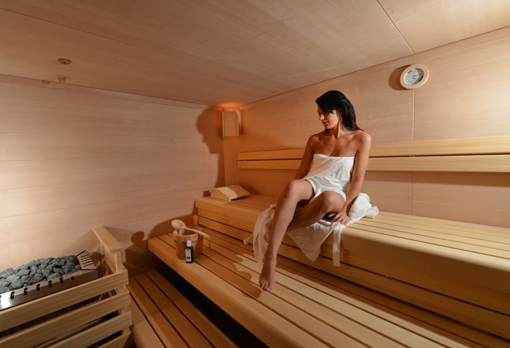 Frau im Handtuch entspannt in der hellen finnischen Sauna aus Holz im Wellnessbereich des ArtHotel Kiebitzberg
